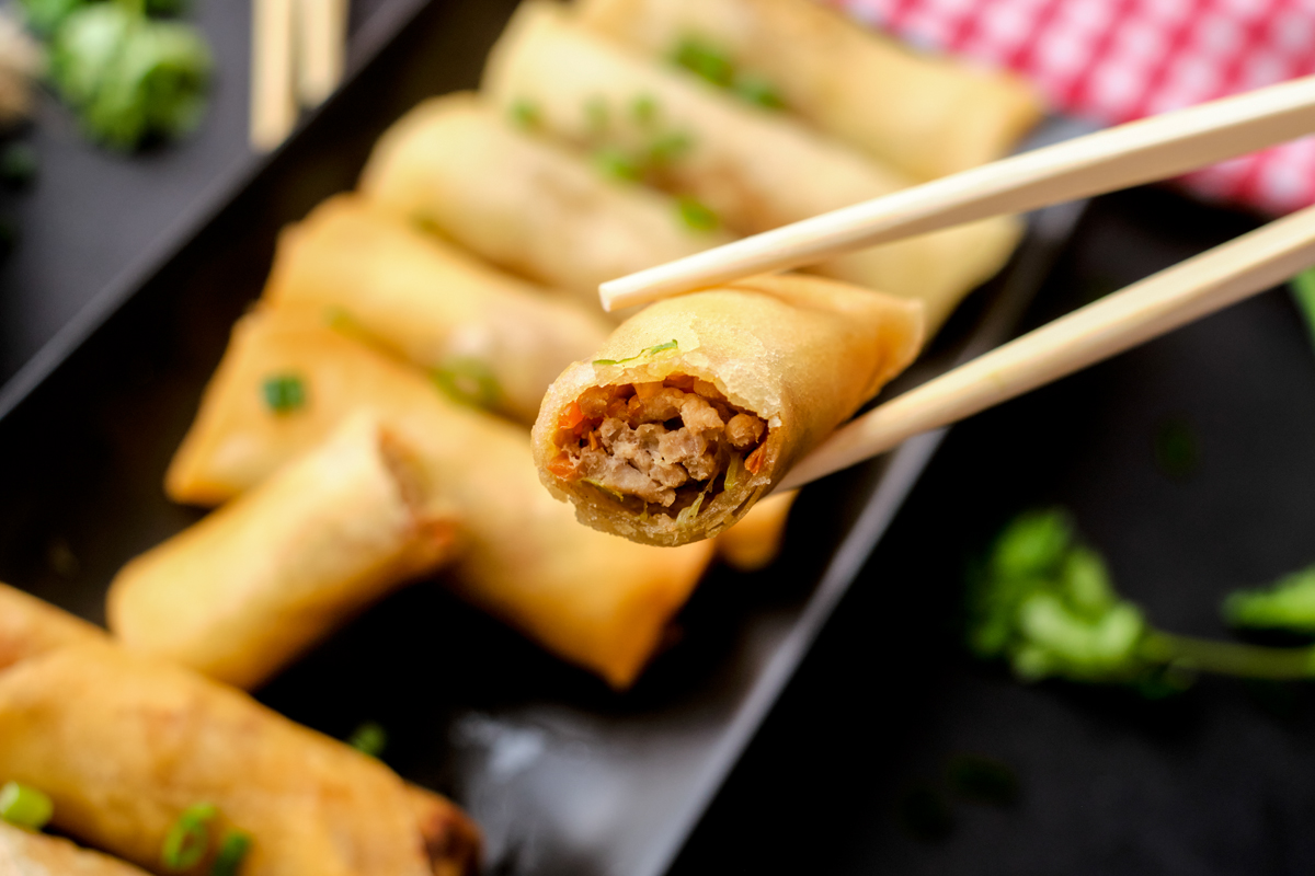chicken and vegetable spring rolls cooked on a long black plate