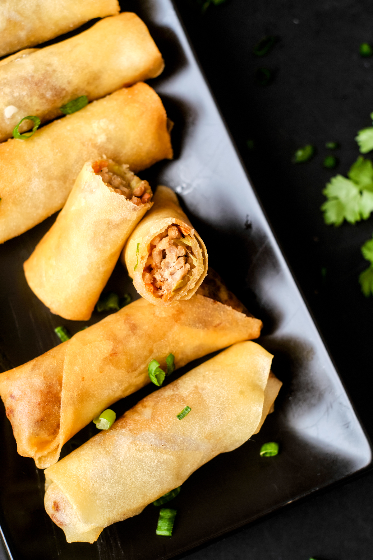 chicken and vegetable spring rolls cooked on a long black plate